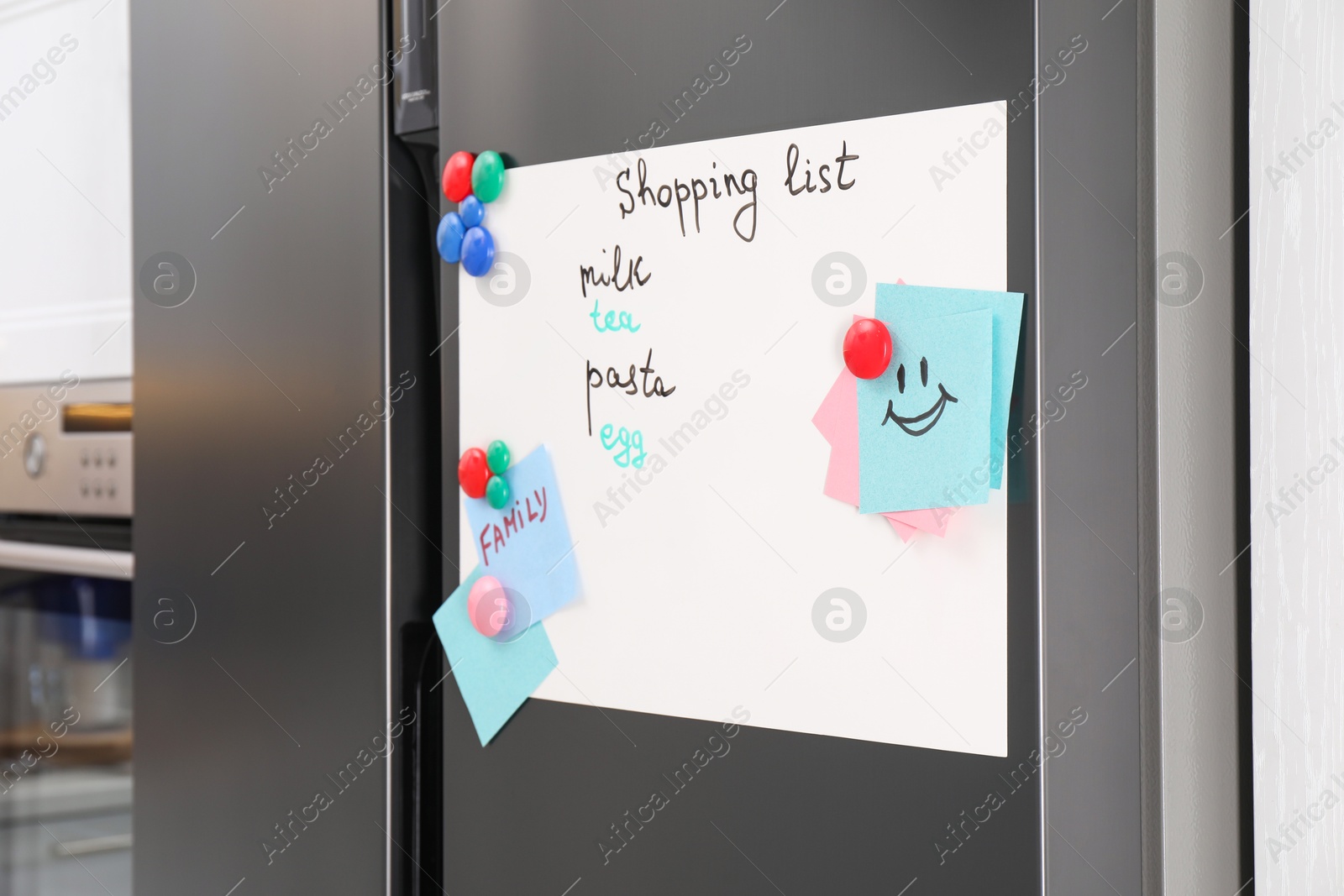 Photo of Magnetic board with shopping list and notes on refrigerator in kitchen