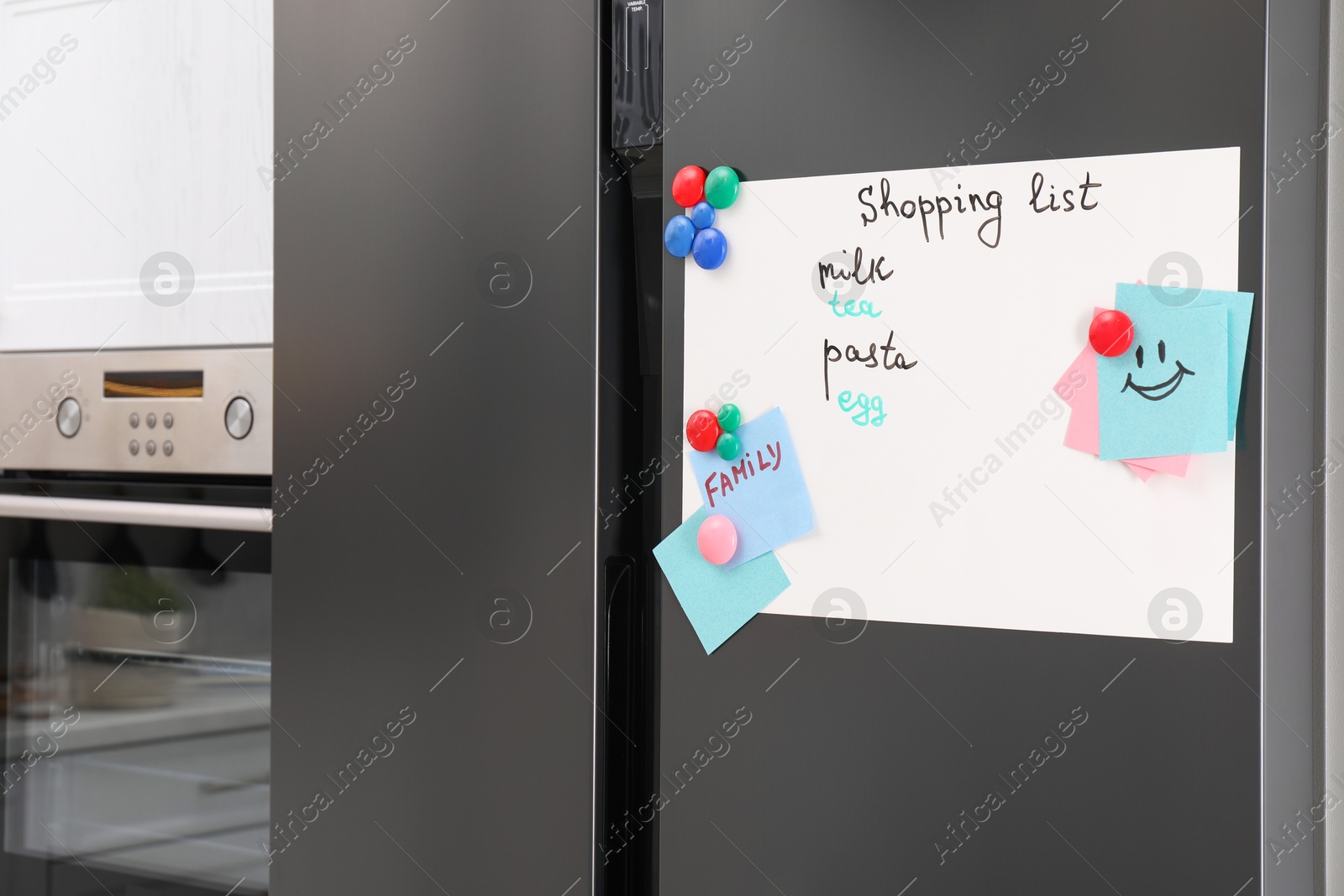 Photo of Magnetic board with shopping list and notes on refrigerator in kitchen