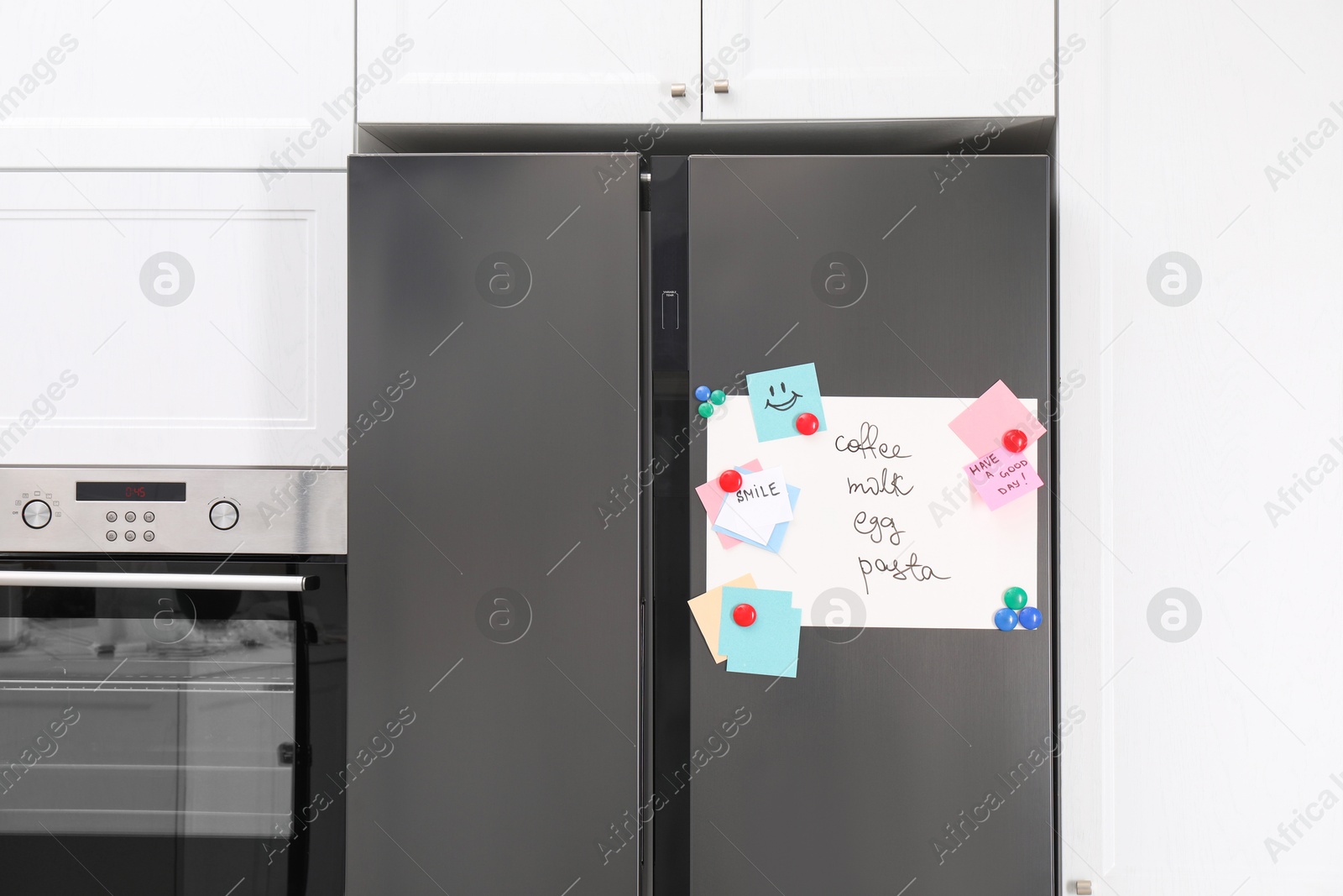 Photo of Magnetic board with shopping list and notes on refrigerator in kitchen