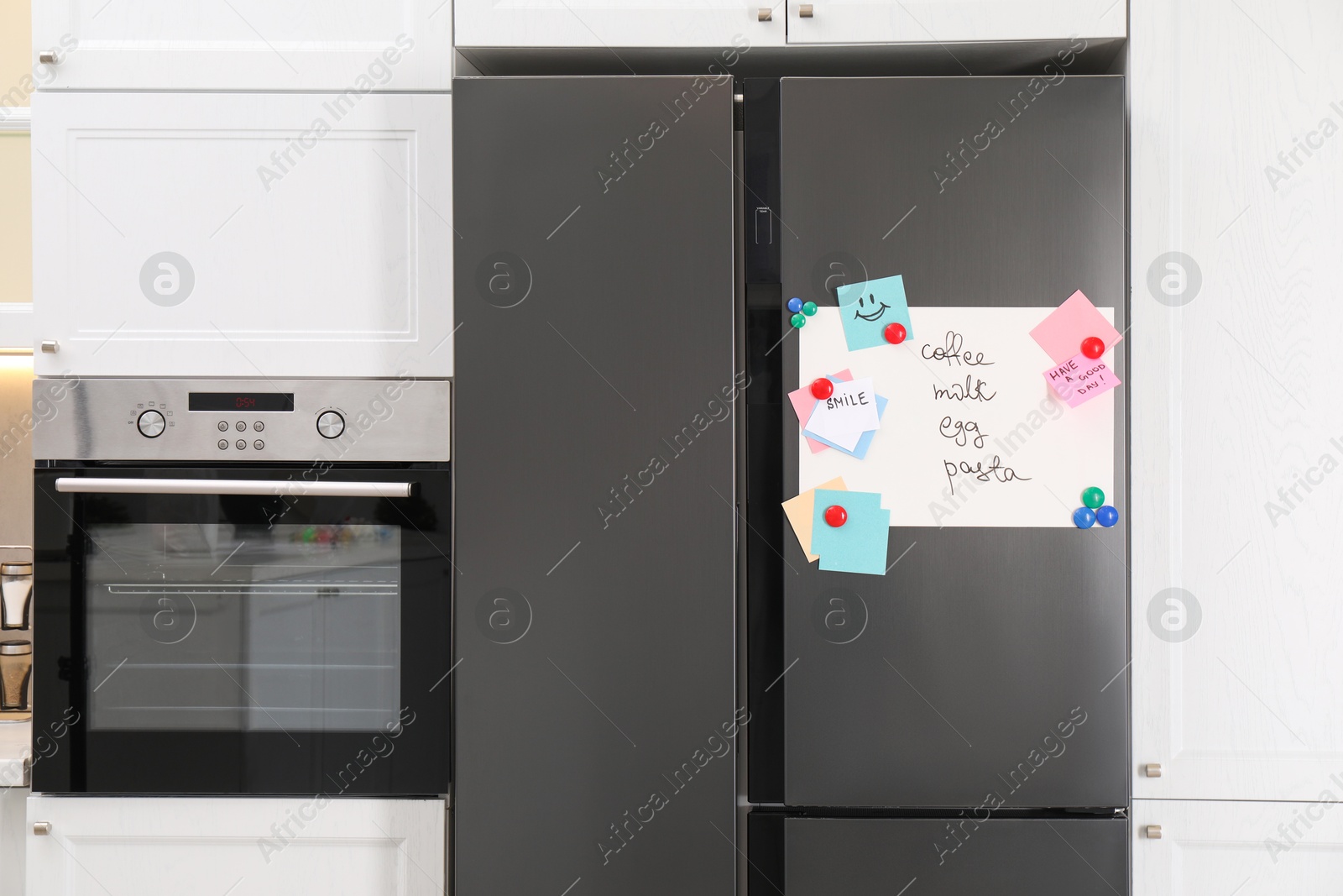 Photo of Magnetic board with shopping list and notes on refrigerator in kitchen