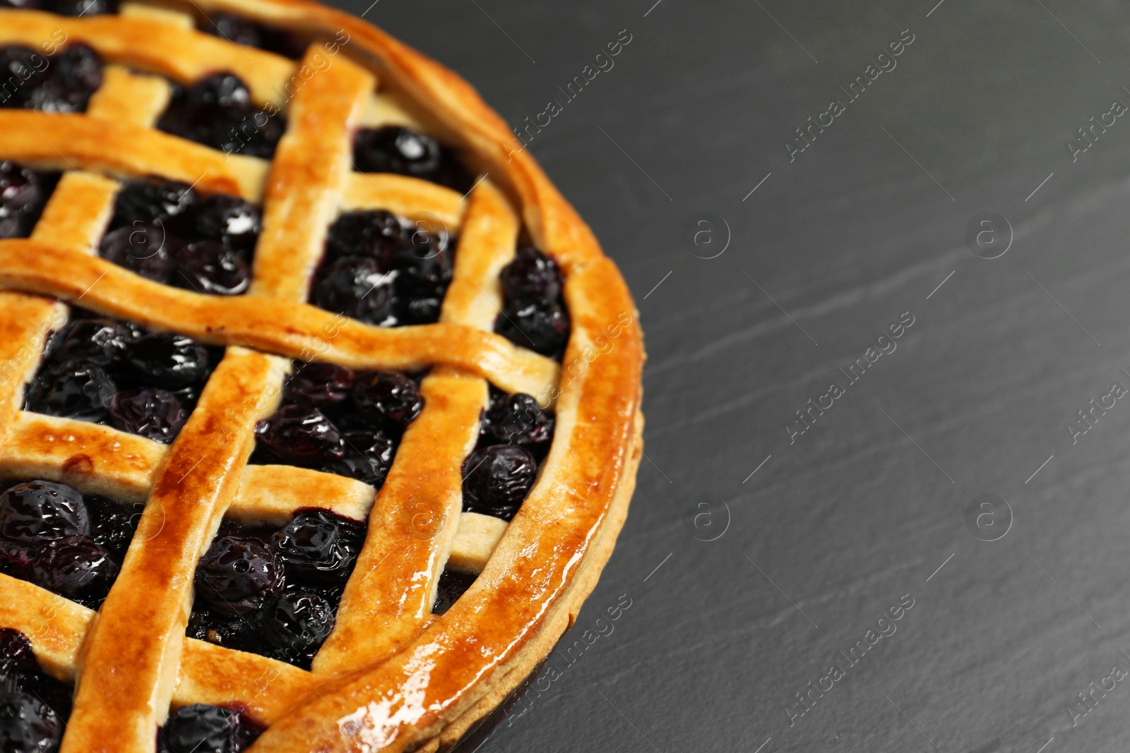 Photo of Tasty homemade pie with blueberries on grey table, closeup. Space for text