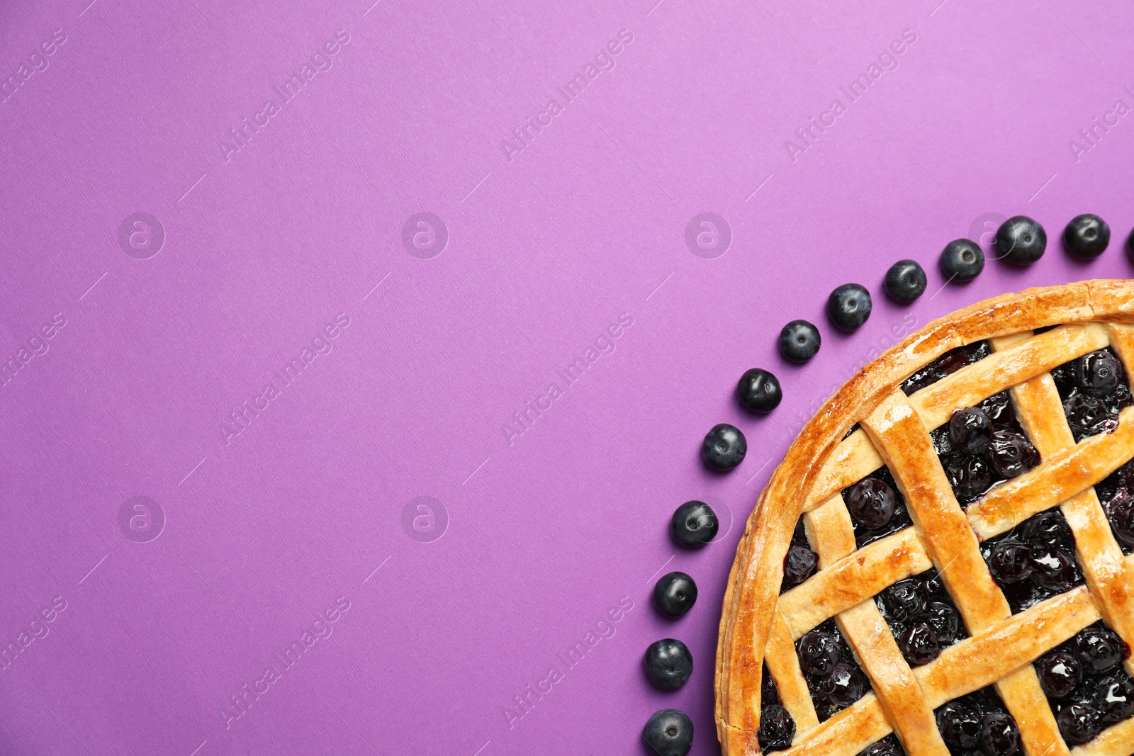 Photo of Tasty homemade pie with blueberries on purple table, top view. Space for text