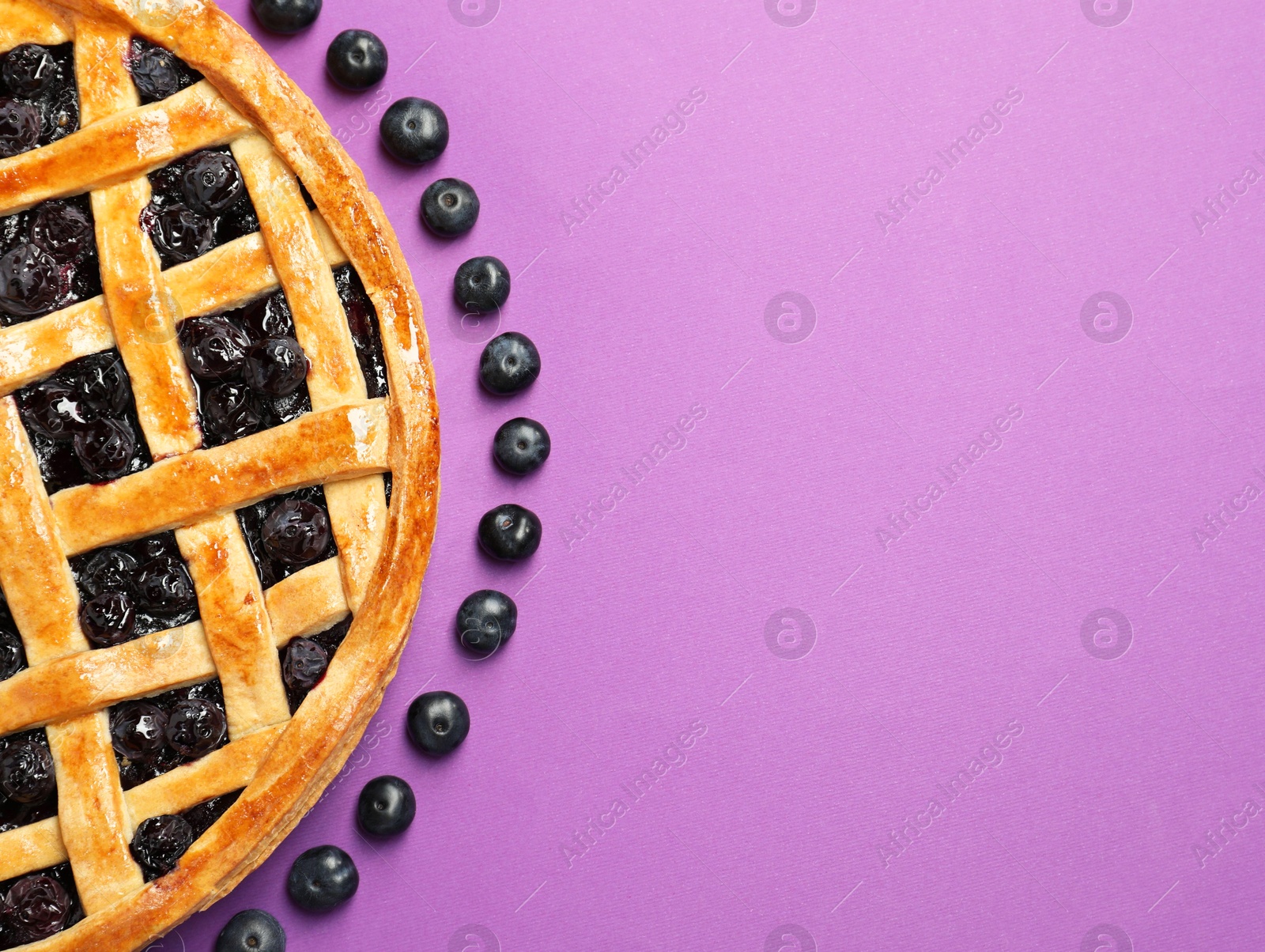 Photo of Tasty homemade pie with blueberries on purple table, top view. Space for text