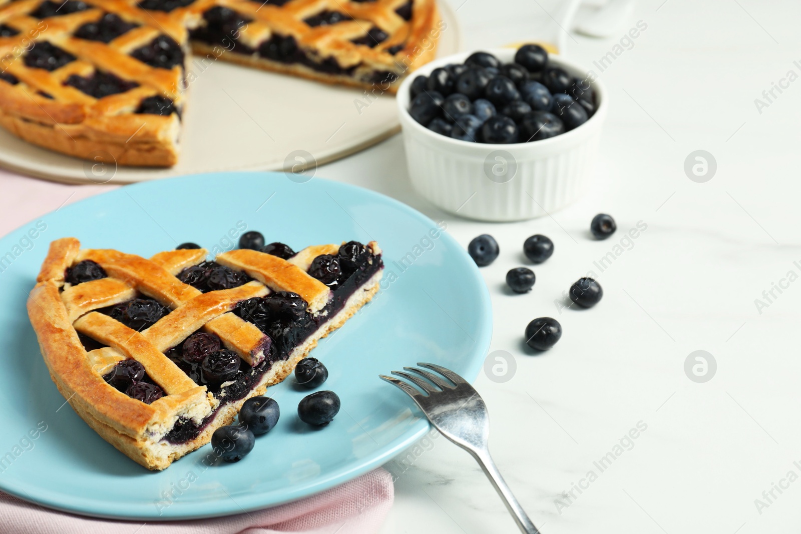 Photo of Piece of tasty homemade pie with blueberries served on white marble table