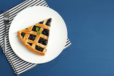 Photo of Piece of tasty homemade pie with blueberries served on blue wooden table, flat lay. Space for text