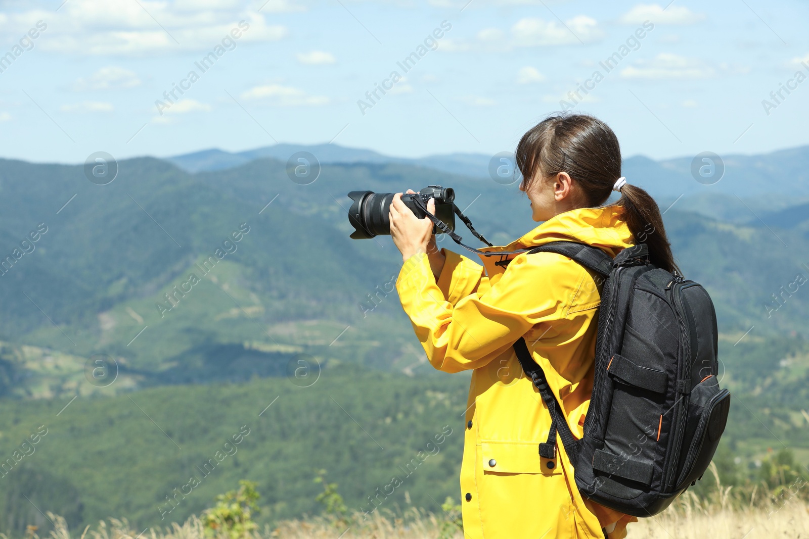 Photo of Photographer with backpack and camera taking picture of beautiful mountains