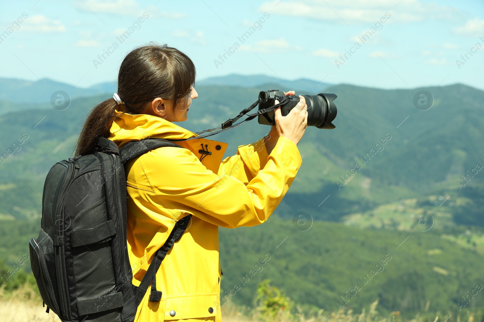 Photo of Photographer with backpack and camera taking picture of beautiful mountains