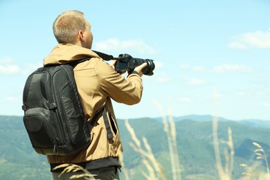 Photographer with backpack and camera taking picture of beautiful mountains. Space for text