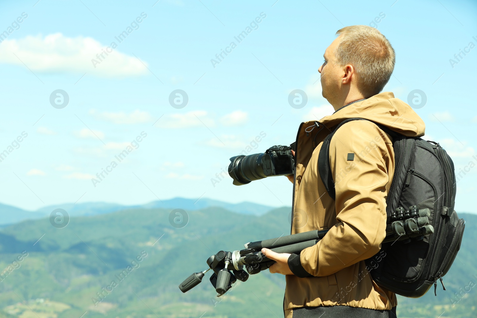 Photo of Photographer with backpack, camera and other professional equipment in mountains. Space for text