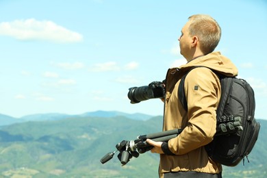 Photo of Photographer with backpack, camera and other professional equipment in mountains. Space for text