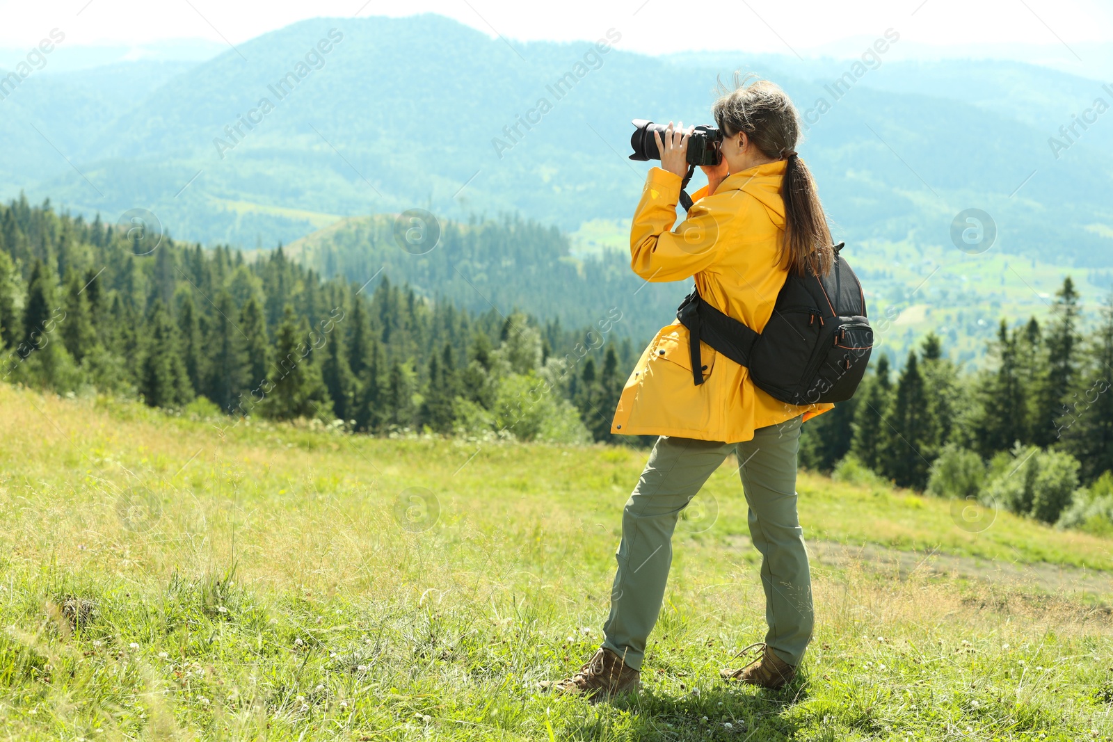 Photo of Photographer with backpack and camera taking picture of beautiful mountains. Space for text