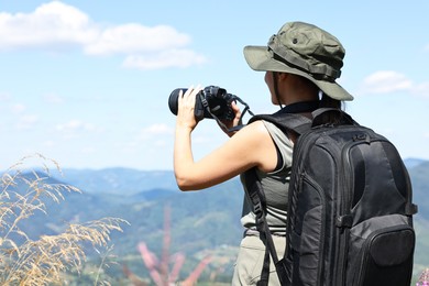 Photographer with backpack and camera taking picture of beautiful mountains