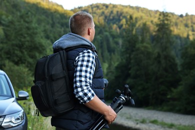 Photo of Photographer with backpack, tripod and camera in beautiful mountains