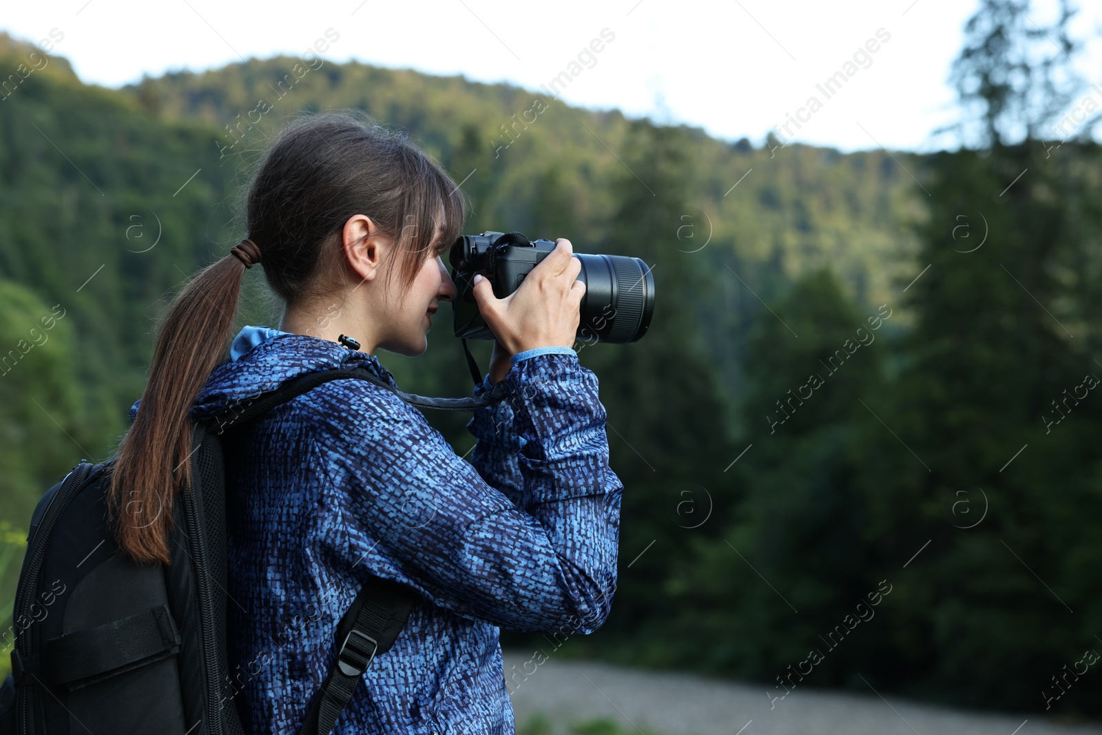 Photo of Photographer with backpack and camera taking picture of beautiful mountains, space for text