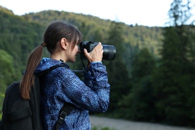 Photo of Photographer with backpack and camera taking picture of beautiful mountains, space for text