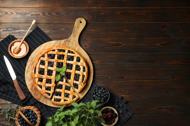 Photo of Tasty homemade pie with blueberries, fresh berries, mint, honey and knife on wooden table, flat lay. Space for text