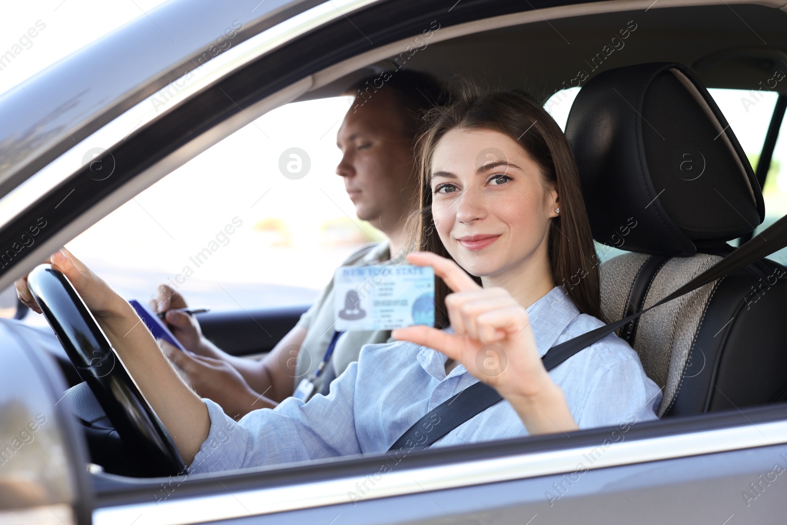 Photo of Driving school. Woman showing driving licence after exam in car