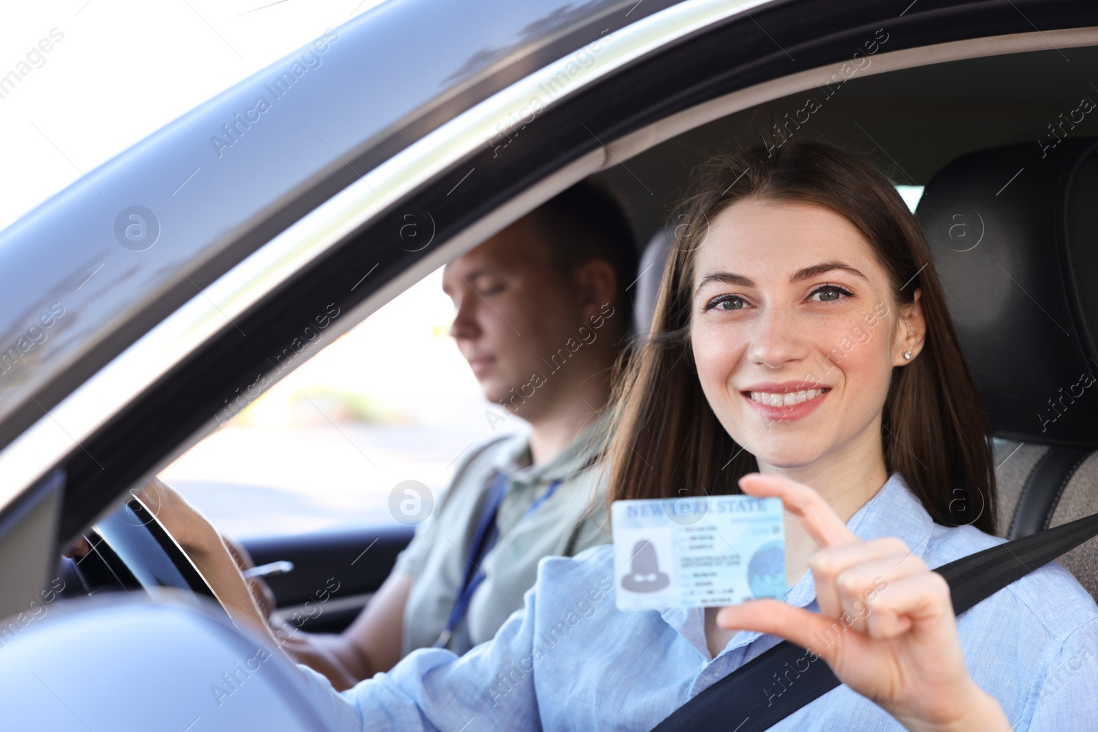 Photo of Driving school. Woman showing driving licence after exam in car