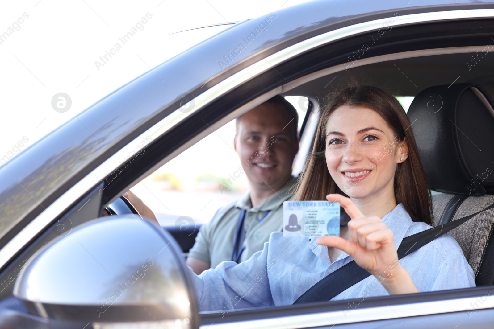 Photo of Driving school. Woman showing driving licence after exam in car