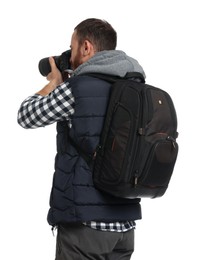 Photographer with backpack and camera taking picture on white background, back view