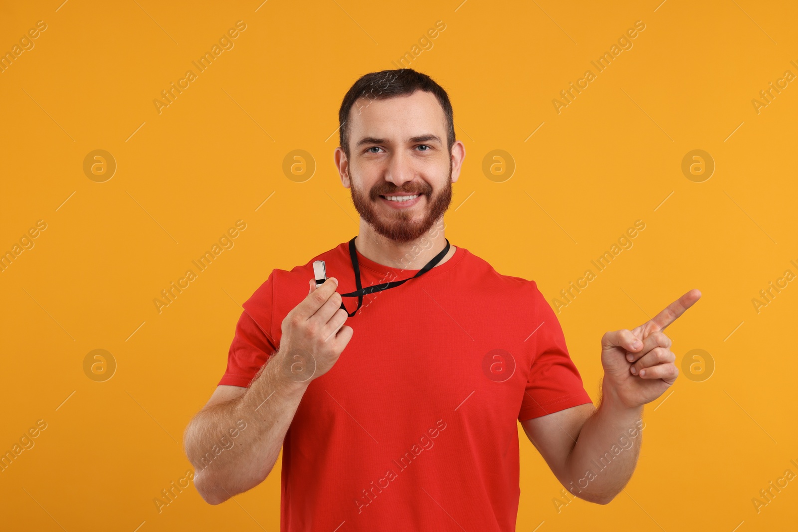 Photo of Happy young man with whistle on orange background