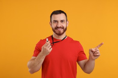 Happy young man with whistle on orange background