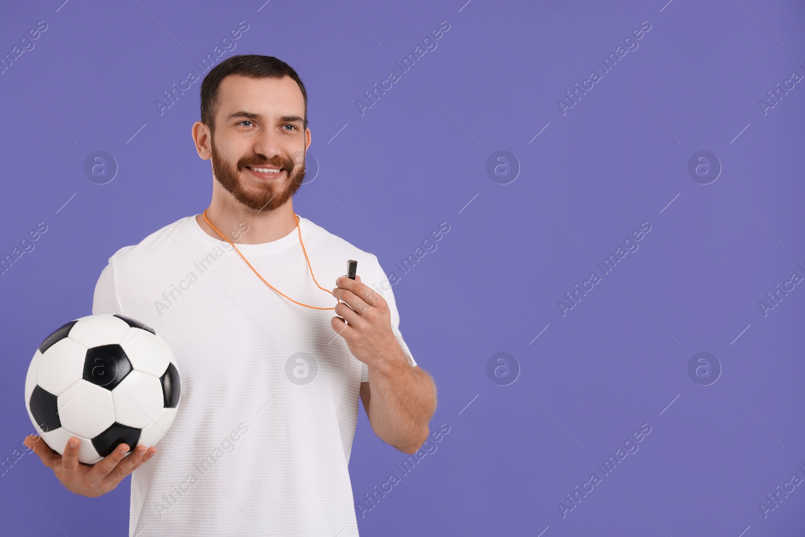 Photo of Happy young man with whistle on purple background, space for text