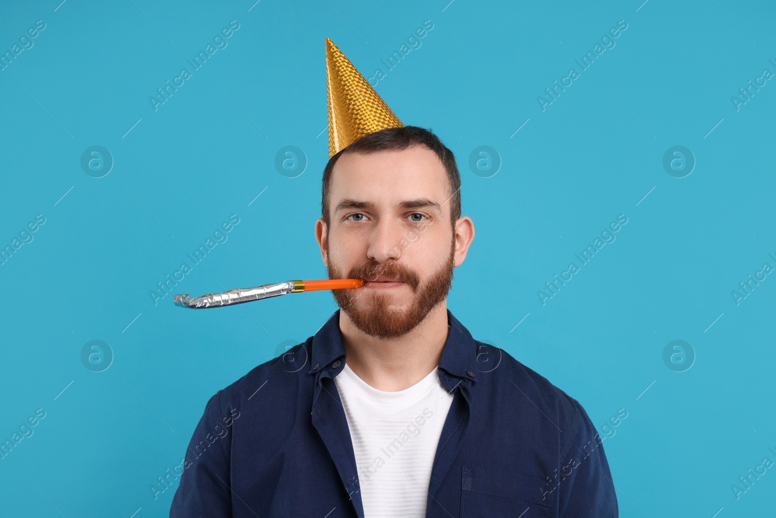 Photo of Man in party hat with blower on light blue background