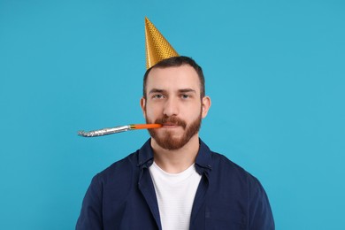 Man in party hat with blower on light blue background