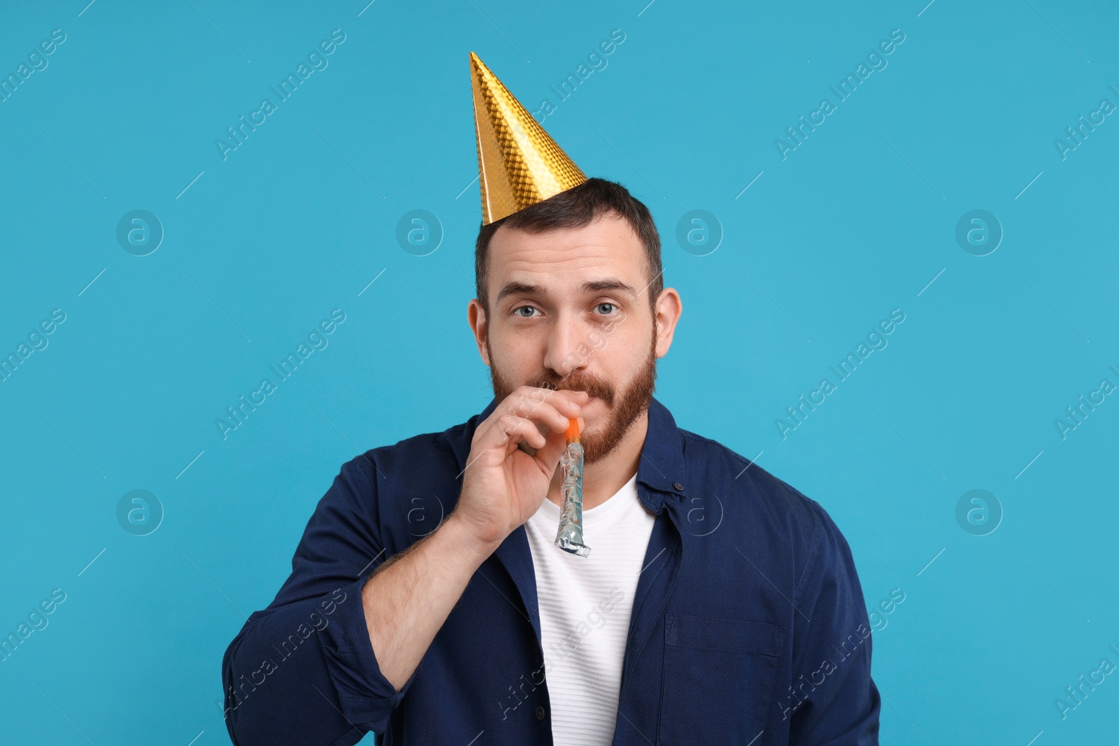 Photo of Man in party hat with blower on light blue background