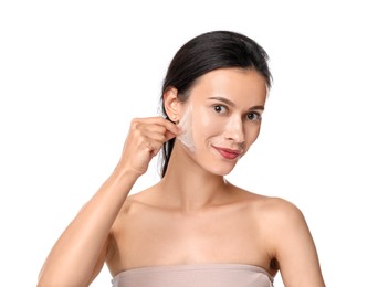 Beautiful woman peeling off face mask on white background