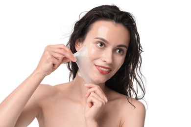 Smiling woman peeling off face mask on white background