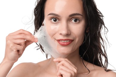 Smiling woman peeling off face mask on white background