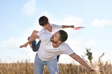 Happy father and son with flag of USA having fun outdoors