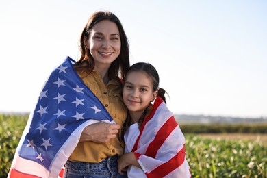 Happy mother and daughter with flag of USA outdoors. Space for text