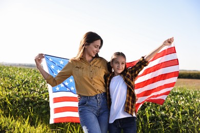 Happy mother and daughter with flag of USA outdoors