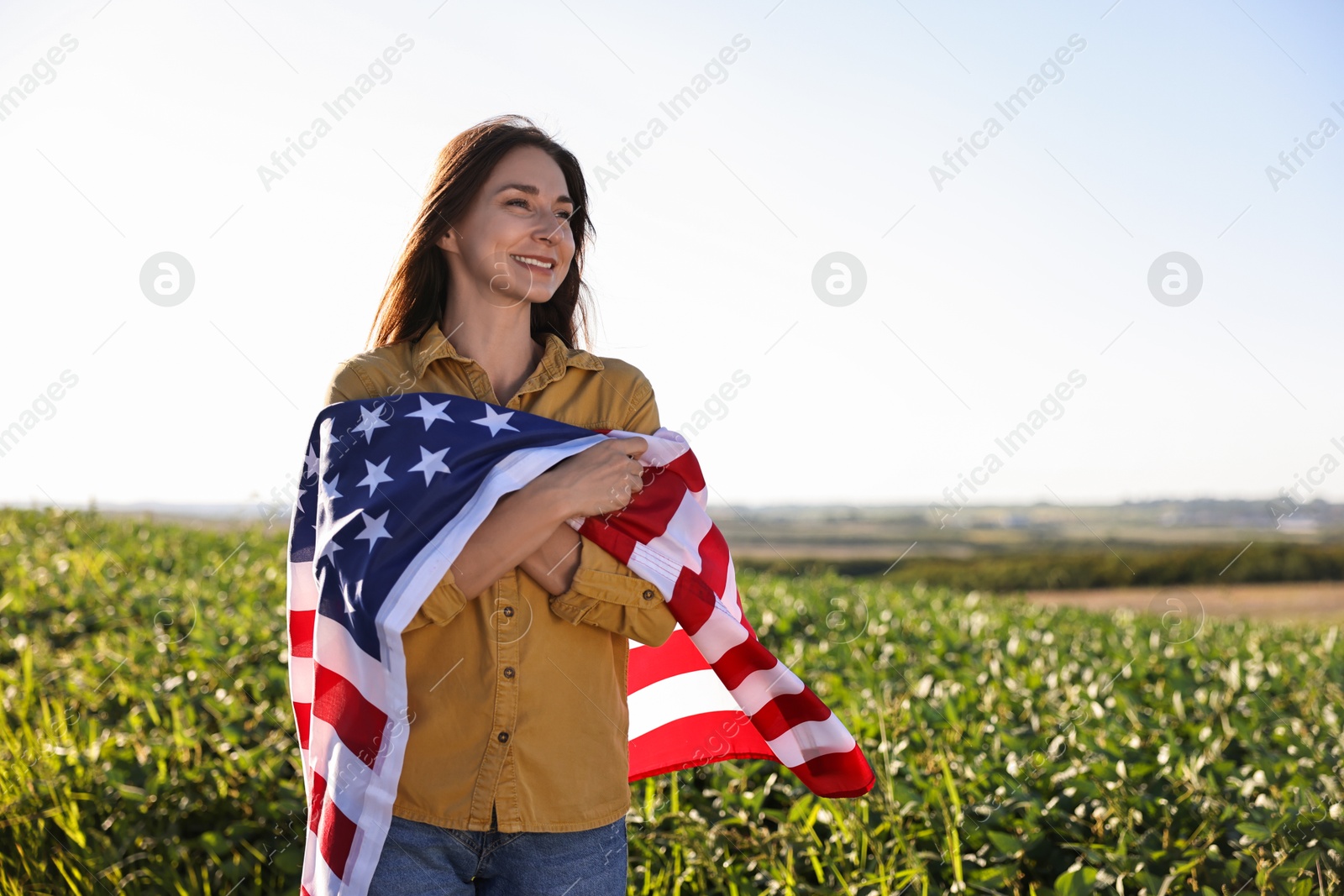 Photo of Happy woman with flag of USA outdoors. Space for text