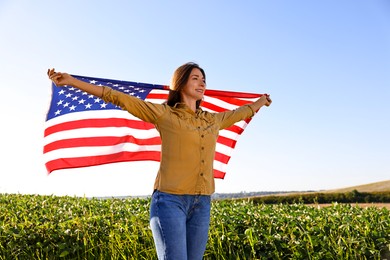 Photo of Happy woman with flag of USA outdoors, low angle view