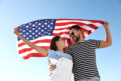 Happy couple with flag of USA outdoors, low angle view