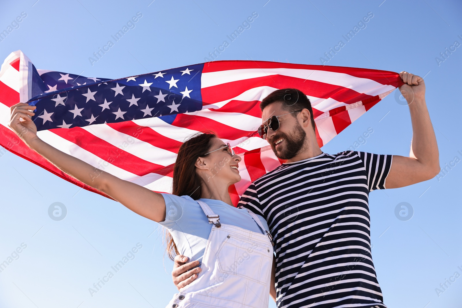 Photo of Happy couple with flag of USA outdoors, low angle view