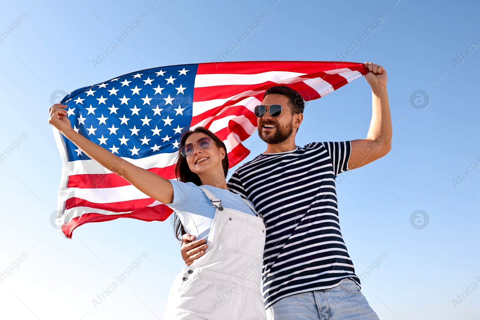 Photo of Happy couple with flag of USA outdoors, low angle view