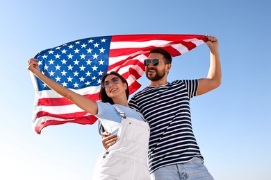 Happy couple with flag of USA outdoors, low angle view