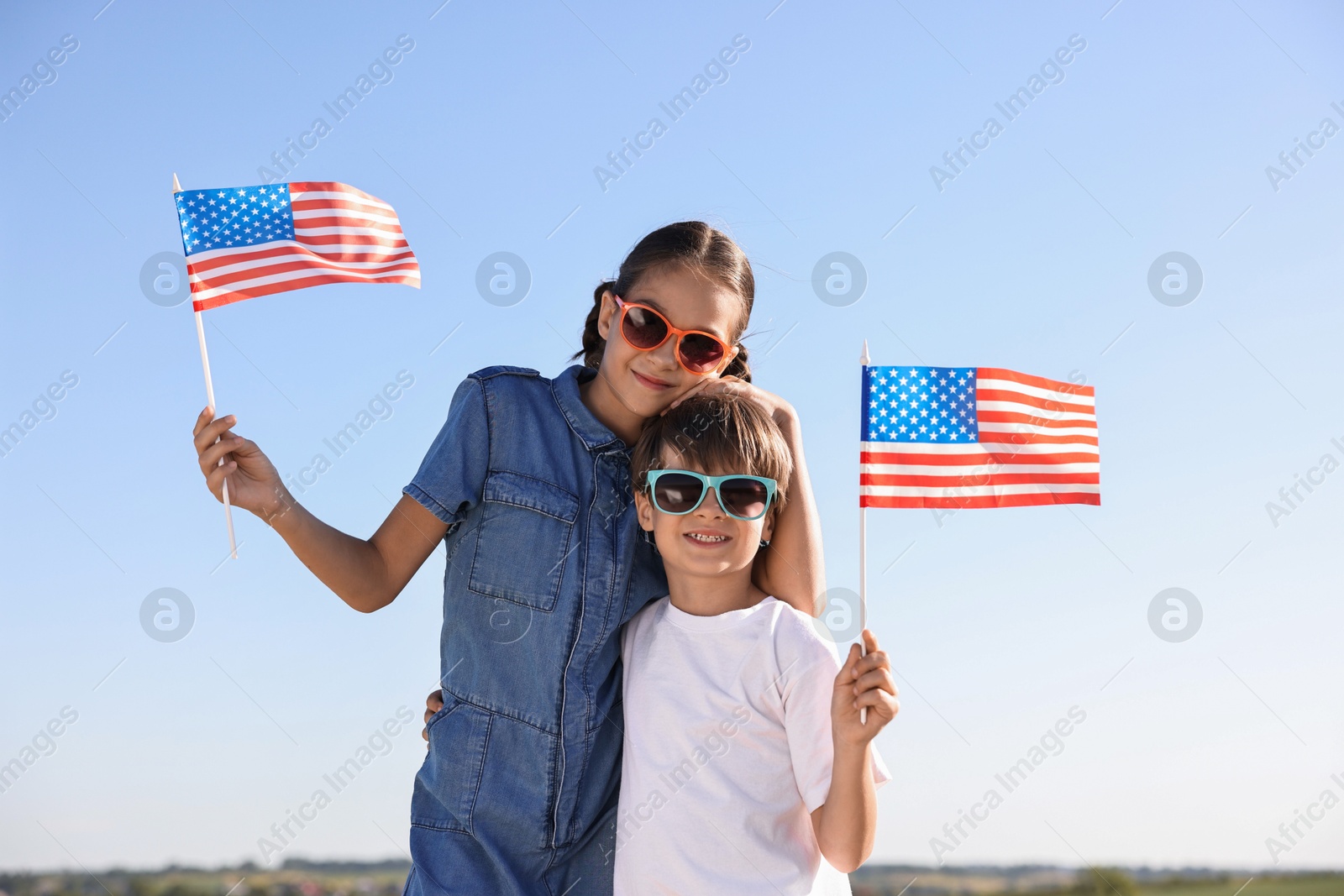 Photo of Brother and sister with flags of USA outdoors