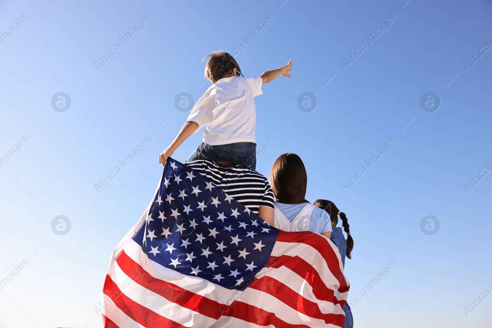 Photo of Family with flag of USA outdoors, back view