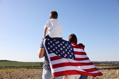 Family with flag of USA outdoors, back view