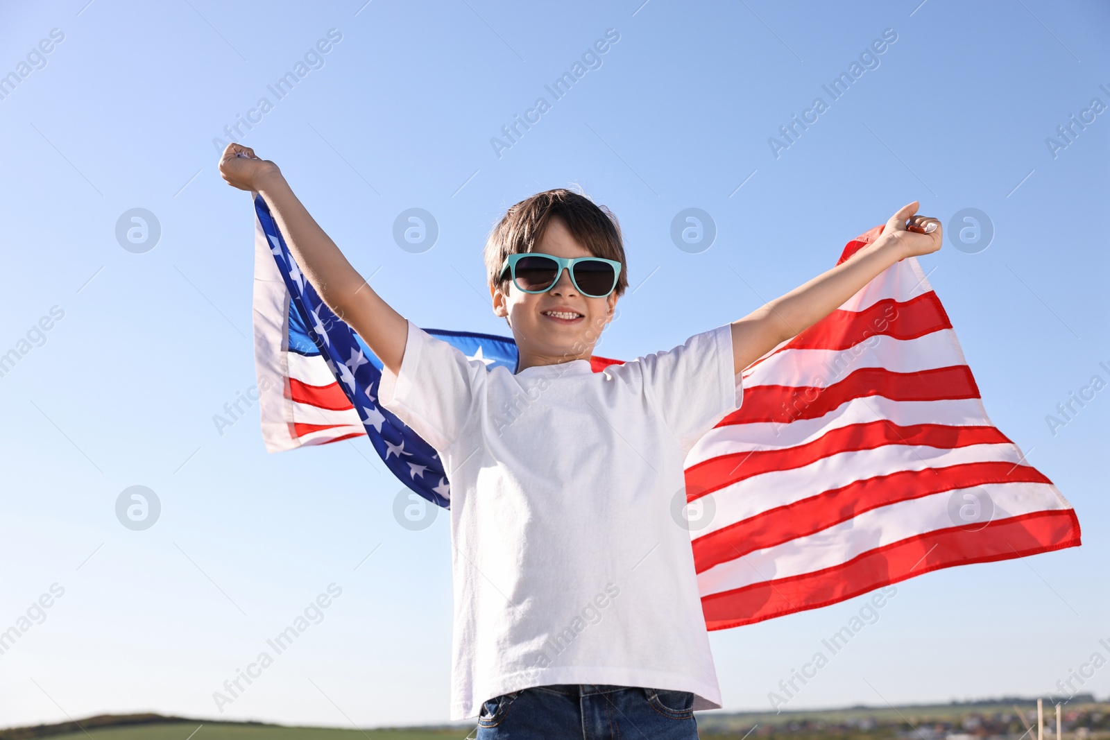 Photo of Portrait of happy boy with flag of USA outdoors