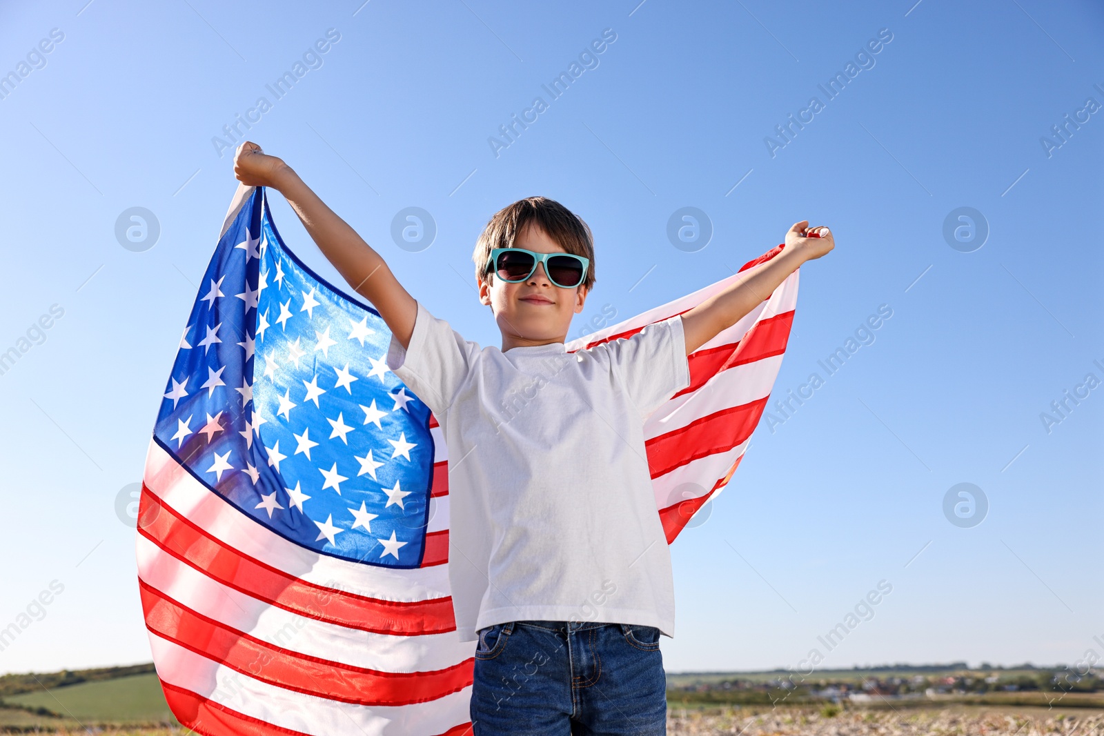 Photo of Portrait of little boy with flag of USA outdoors