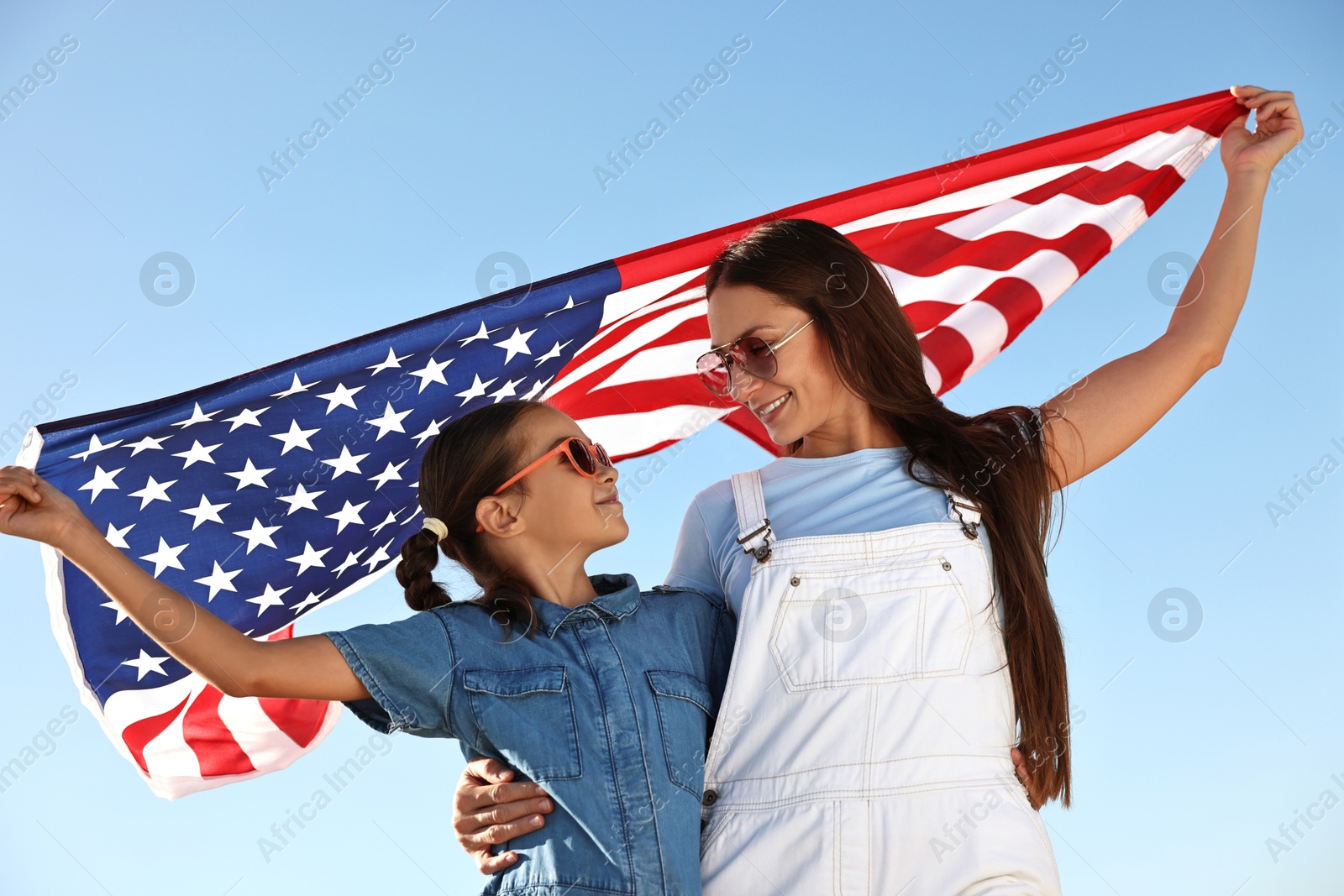 Photo of Happy mother and daughter with flag of USA outdoors