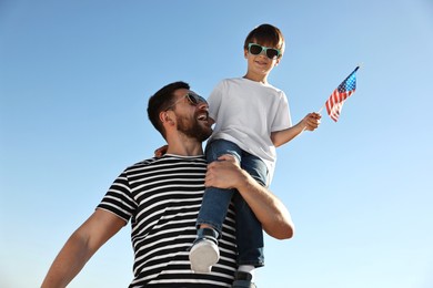 Photo of Happy father and son with flag of USA outdoors, low angle view