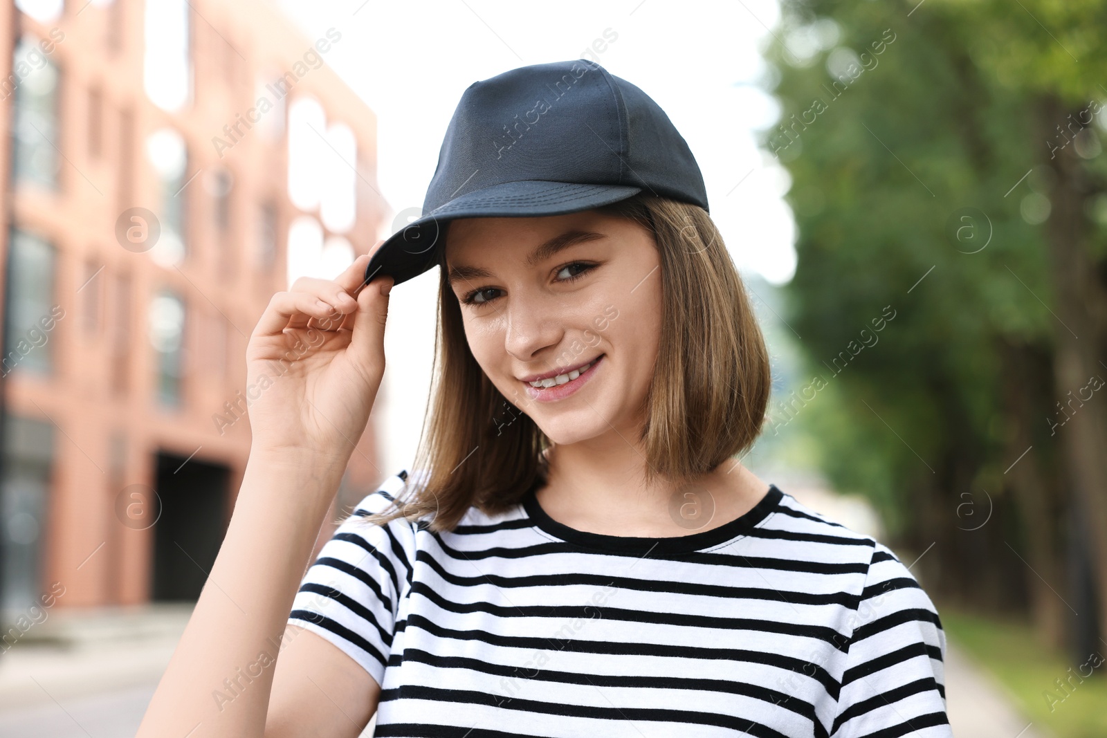 Photo of Portrait of smiling woman in baseball cap outdoors